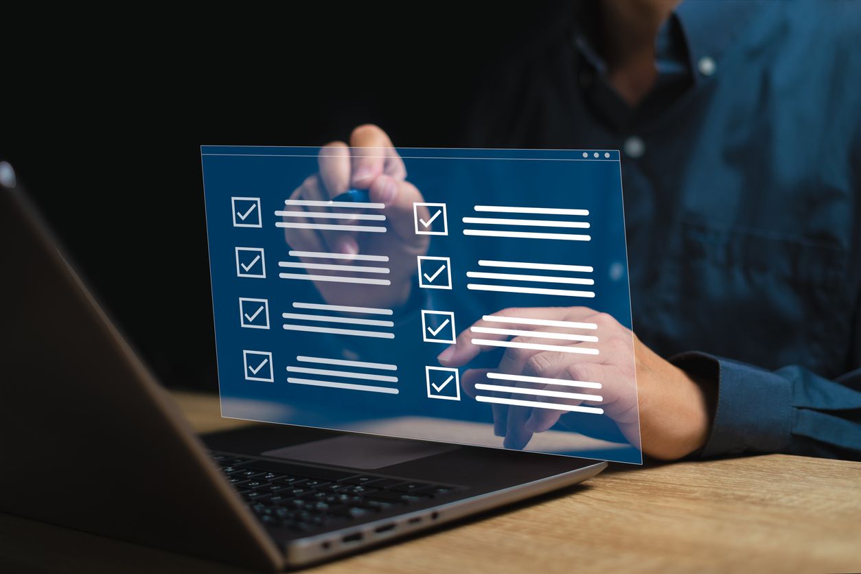 Man working on laptop and going over virtual checkmarks that goes out of the laptop