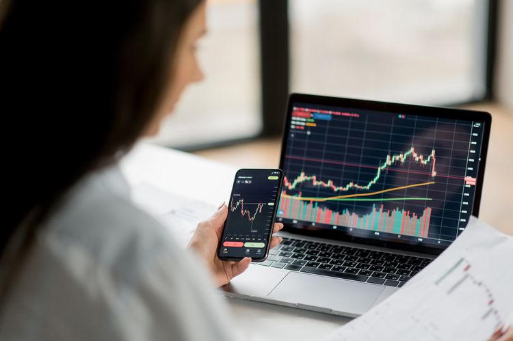 Woman looking on chart in mobile, paper and laptop